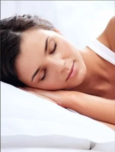 A woman sleeping peacefully in a white daytime setting.
