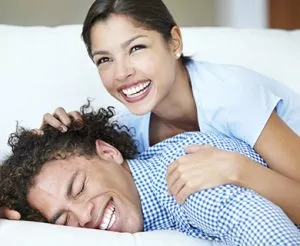 A man and woman smiling in bed together.